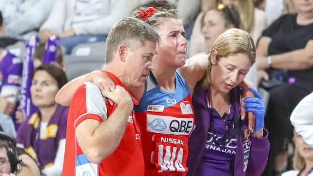 Devastated: NSW Swifts captain Maddy Proud is helped off the court on Sunday after injuring her knee.