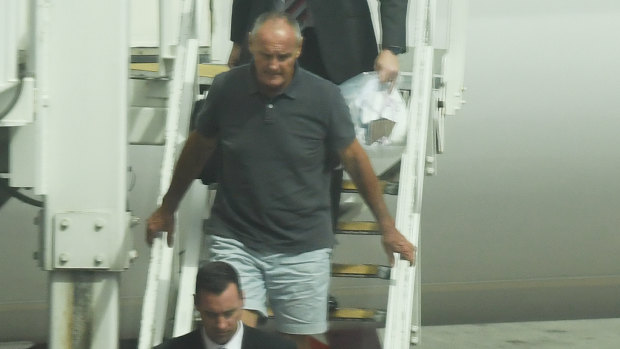 Chris Dawson is escorted by NSW Police detectives off a Qantas flight after being extradited from the Gold Coast in December.