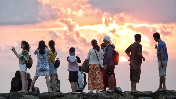 Chinese tourists watch the sunset on Kuta beach.
