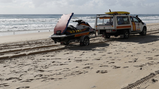 A surf life saving crew drives past the scene where the body of an infant was found at Surfers Paradise.