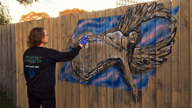 Miriam Fee creates work on a wooden fence.