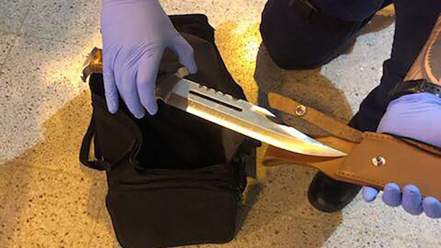 A police officer holds a hunting knife seized after the stabbing.