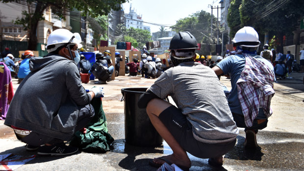 Protesters await a police assault with water buckets and wet blankets in Yangon in March 2021.