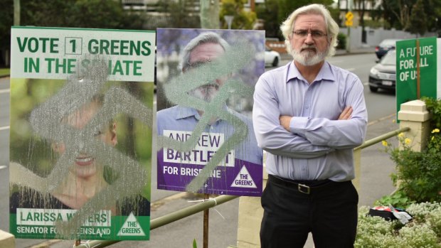 Greens' Brisbane candidate Andrew Bartlett next to vandalised placards on Sandgate Road in Clayfield.