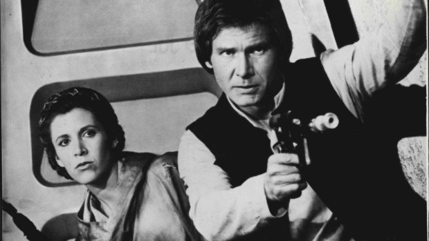 Harrison Ford, aka Han Solo, brandishing his blaster alongside Carrie Fisher's Princess Leia.