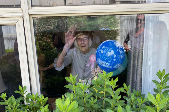 Gladys Nutbean waves to relatives through her window. 