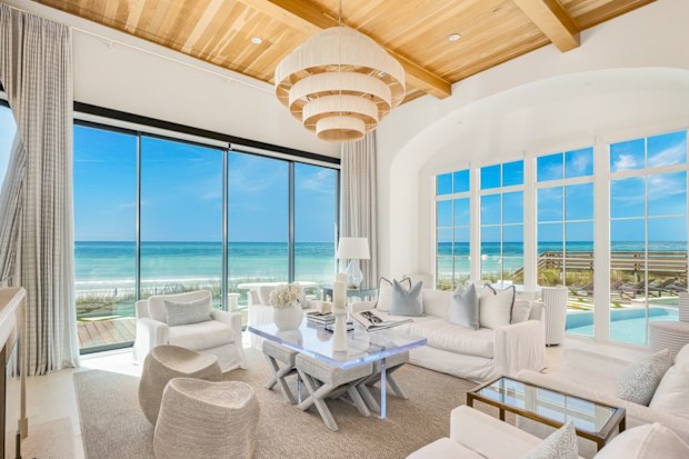 An all white living room with huge windows and ocean views