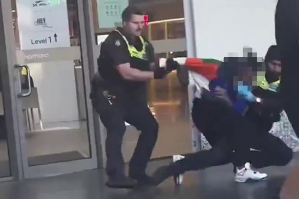 Police wrestle a man to the ground at Northland Shopping Centre on Sunday.