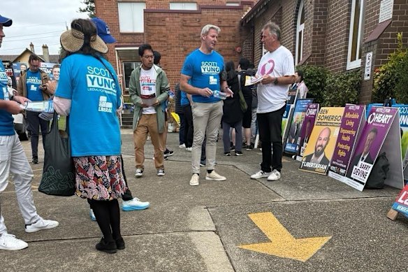 Gareth Hales (centre, in blue Scott Yung T-shirt), the multimillionaire son of Plymouth Brethren Christian Church leader Bruce Hales, at the Bennelong polling booth on April 30.