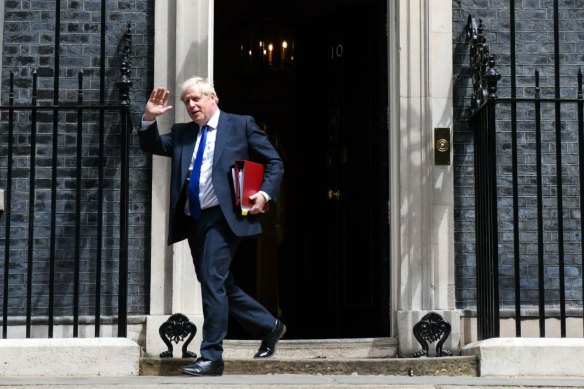 Boris Johnson waves to waiting media outside his office after the resignation of several of his ministers earlier this week.