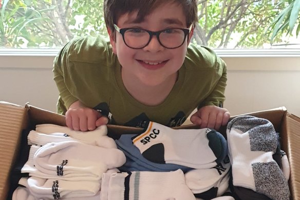 Benjy Orwin, 11, with some of the thousands of pairs of socks he has helped donate.