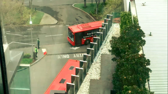 Guards and police SkyBus services arriving at Crown Promenade on Thursday. The buses carried returned overseas travellers beginning their mandatory 14-day hotel stay.