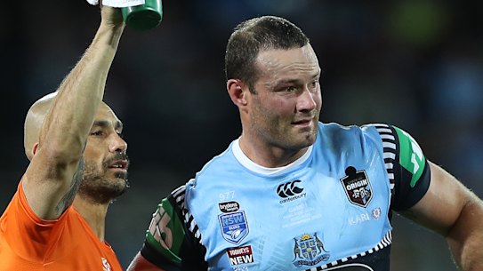 Boyd Cordner is helped from the field by Roosters and Blues trainer Travis Touma.