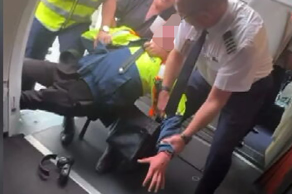 A still from passenger Daniel Defina’s footage of the teenager being restrained by a Jetstar employee, Barry Clark and the pilot.