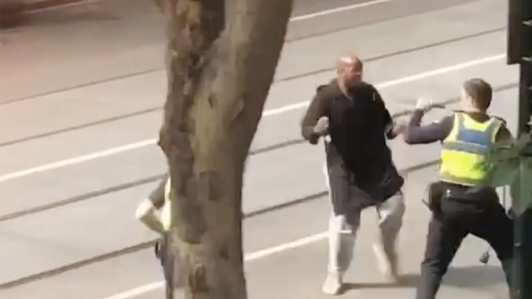 Police confront the alleged attacker on Bourke Street.