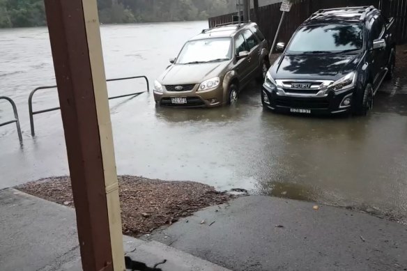 Cars sit in water next to the river.