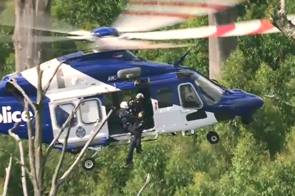 A police helicopter lowers officers to the crash site.