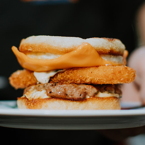 Warkop’s breakfast muffin served with a house-made sausage patty, fried egg, optional hash brown (pictured) and “Bazzinga sauce”.