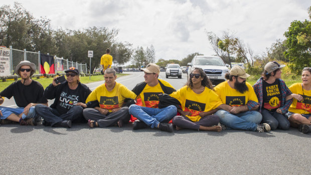 Protesters sit in the middle of the road in an attempt to stop the Queens Baton relay.