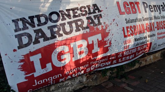 FILE - In this March 17, 2016 file photo, a man walks past an anti-LGBT banner erected by an ultra-conservative Islamic group in Jakarta. Indonesia's Constitutional Court is considering whether to make gay sex a crime after accepting a judicial review petition from Islamic activists. A group calling itself the Family Love Alliance says an existing law that criminalizes sex between adults and minors of the same gender, and which mandates prison sentences of up to 15 years, should be amended to also apply to sexual acts between adults of the same gender. Rita Hendrawaty, chairwoman of the group, said Wednesday, Aug. 3, it was not trying to criminalize lesbian, gay, bisexual and transgender people. Letters on the banner read: "Indonesia is on LGBT emergency" and "Gay people are contagious, save the young generation from LGBT people." (AP Photo/Tatan Syuflana, File)