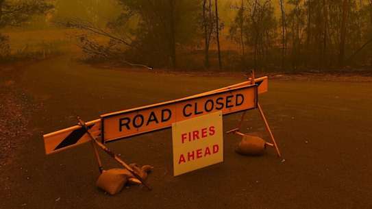 A road closure sign on the intersection of The River Road and the Kings Highway which are both closed due to the fire near Batemans Bay. 1st January, 2020. Photo: Kate Geraghty/SMH