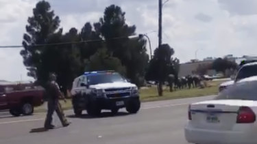 In this image made from video provided by Dustin Fawcett, police officers guard on a street in Odessa, Texas.