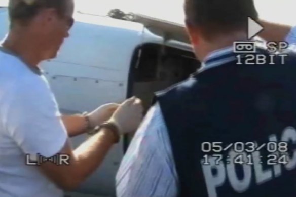 A handcuffed Santos assists police searching the plane at Jandakot Airport. 