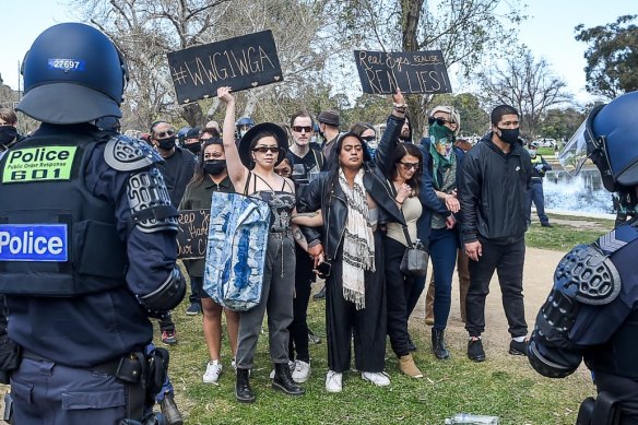 A woman at an anti-lockdown rally in Melbourne holds up a sign with the hashtag "#WWG1WGA", which stands for "where we go one, we go all".