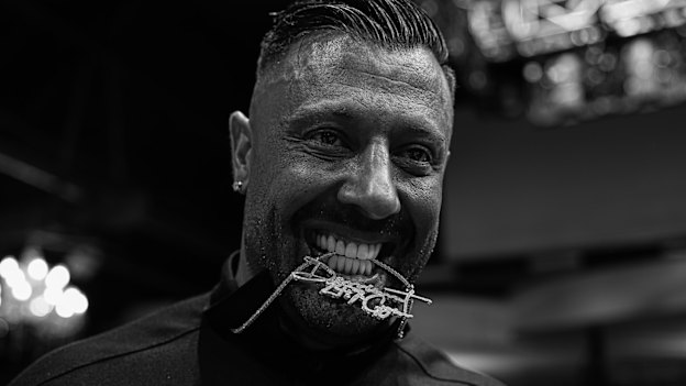 Solomos bites into a bejewelled Derrimut necklace at a boxing event in August last year.