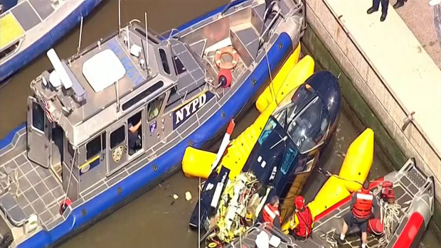 New York City police and fire departments work to secure a helicopter to the dock after it crashed in the Hudson River.