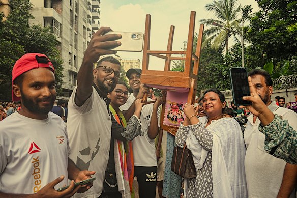 People with a chair from ousted prime minister Sheik Hasina’s official residence on August 5 after Hasina fled to India. 