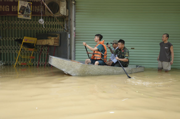 Rescue officers carry people on boat in a flooded street in the aftermath of Typhoon Yagi, in Hanoi.