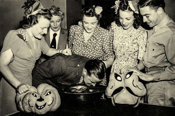 An American soldier bobs for apples watched by partygoers in 1943.