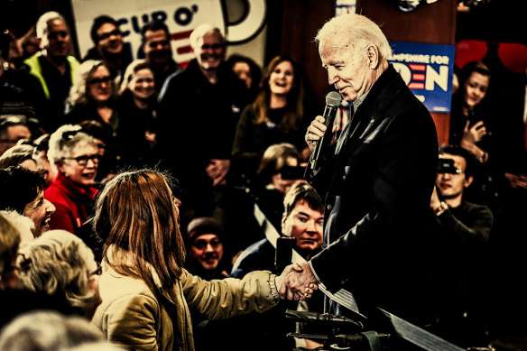 Joe Biden shakes hands with a voter in New Hampshire ahead of the state’s primaries in 2020.