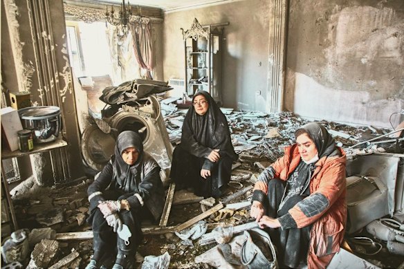 Women sit in a residential building hours after it was hit by an airstrike in the west of Tehran on March 30.