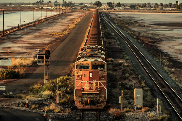 A BHP freight train carrying iron ore travels along a rail track towards Port Hedland, Australia in 2019