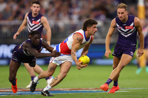 Tom Liberatore handballs while being tackled by Michael Frederick during the Dockers loss to the Bulldogs on Friday night. 