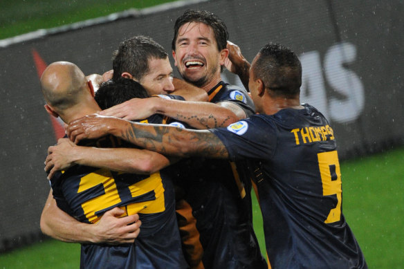 Harry Kewell is mobbed by teammates after scoring for Australia.