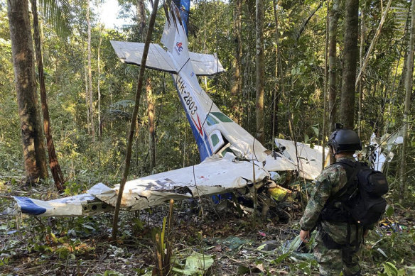 Bir asker, Kolombiya'nın Caqueta eyaletindeki Solano ormanına düşen Cessna C206'nın enkazının önünde duruyor.