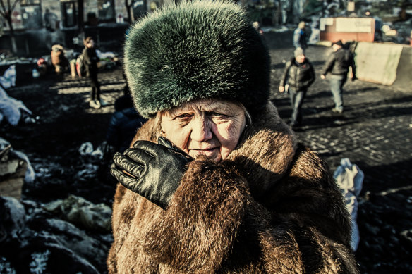 A woman gazes at a police line from a barricade during the Maidan Revolution, an uprising in Kyiv in 2014.