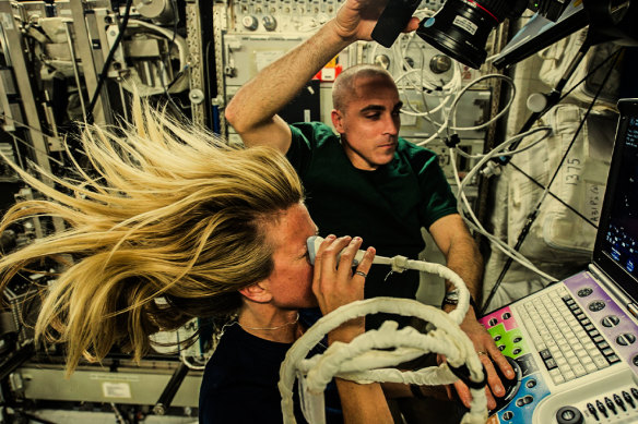 Astronaut Karen Nyberg, helped by astronaut Chris Cassidy, performs an eye ultrasound scan on the International Space Station in 2013.
