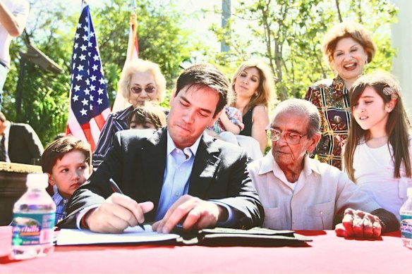 In Miami, Florida, Marco Rubio is flanked by his father, Mario, right, and two of his children as he signs documents ahead of his Senate run in 2010, which he went on to win.