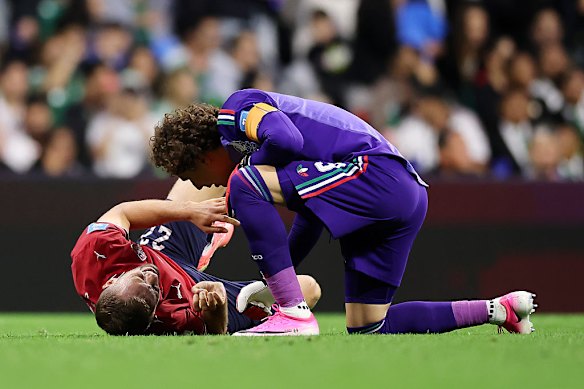 Mexico’s Guillermo Ochoa speaks with to Czechia’s Tomas Soucek as he awaits medical attention.