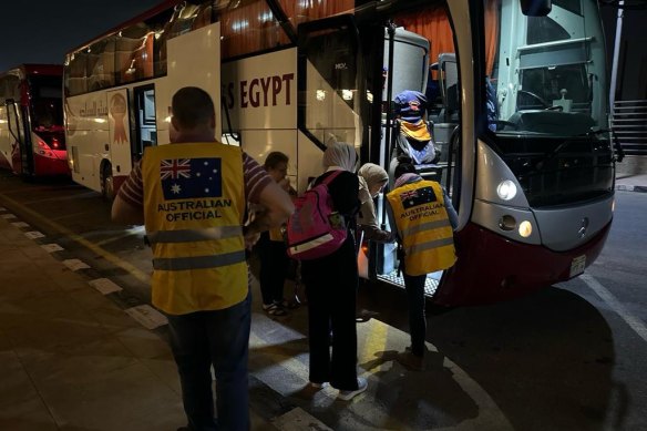 Consular officials helping evacuated Australians on to a coach for Cairo at the Rafah crossing from Gaza.