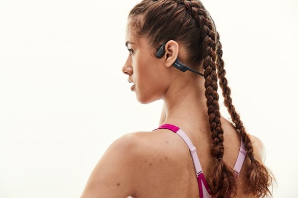 Aftershokz headphones use bone conduction pads in front of and behind the ear to provide sound.