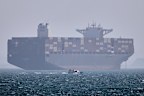 A container ship sits at anchor as a small motorboat passes in the foreground in the Strait of Hormuz off Bandar Abbas, Iran, Saturday, May 2, 2026