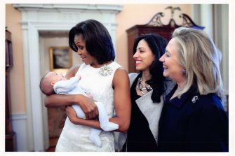 Michelle Obama, then US First Lady, cradles Abedin’s son, Jordan, as Hillary Clinton looks on. 