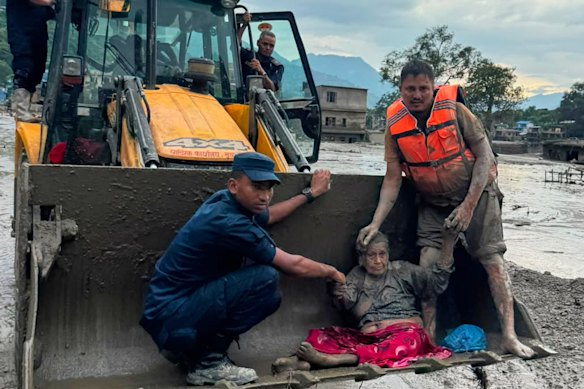 Rescuers use an earthmover to carry a victim of flash flooding to safety along the Trishuli River in Nepal’s Nuwakot district.