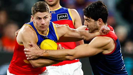 Dayne Zorko of the Lions is tackled by Christian Petracca of the Demons.