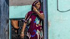 A Dalit woman stands at the entrance to a house in India. 